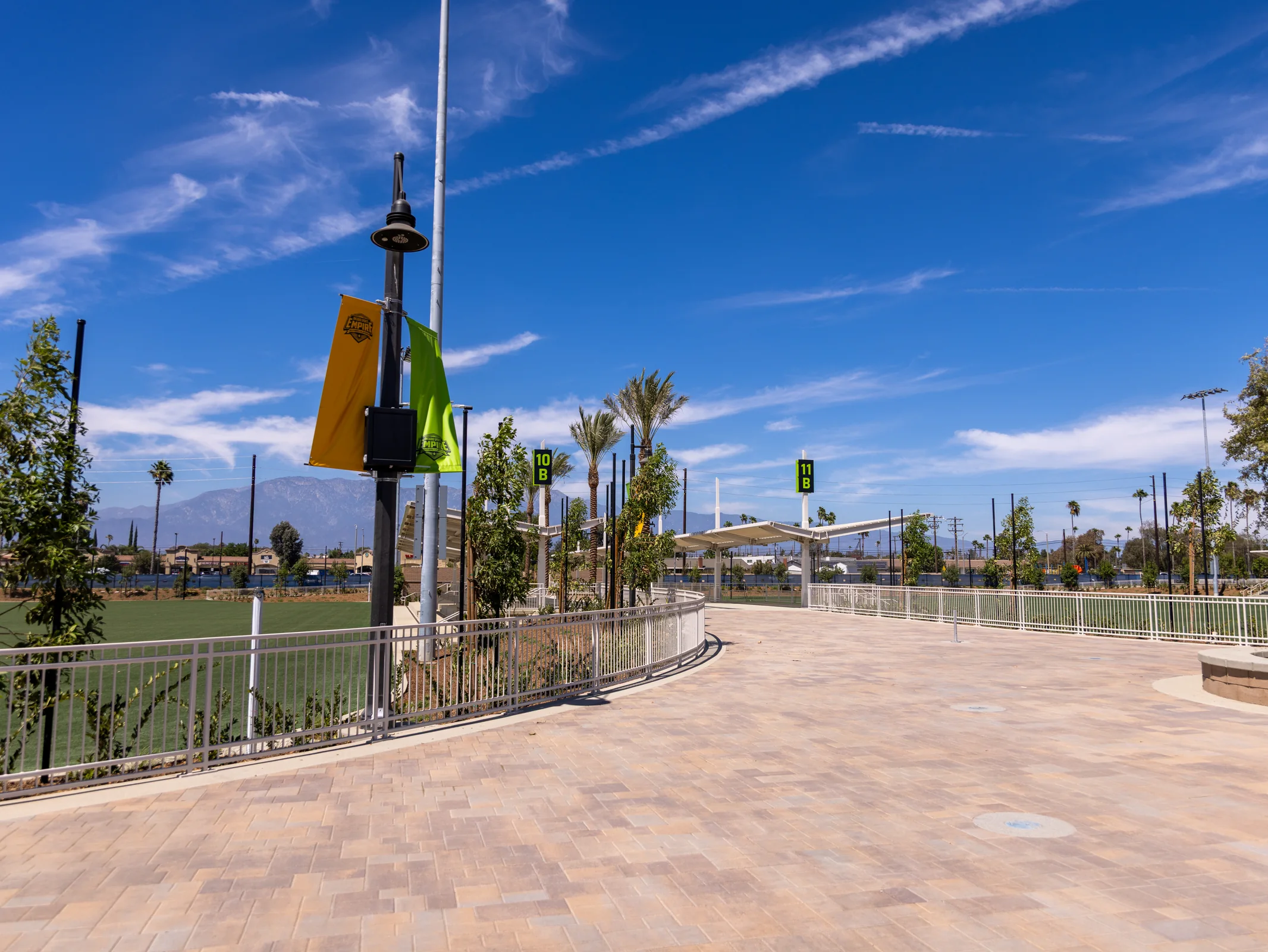 Wide paved promenade, field signs and shade structures at Ontario Sports Empire
