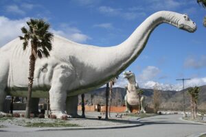 Dinny the Dinosaur and Mr Rex at the Cabazon Dinosaurs with mountains behind them