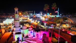 Illuminated fairground rides and castle-style buildings at the Riverside County Fair and National Date Festival