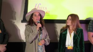 A speaker holding a microphone beside another participant at Yucca Valley Film Festival