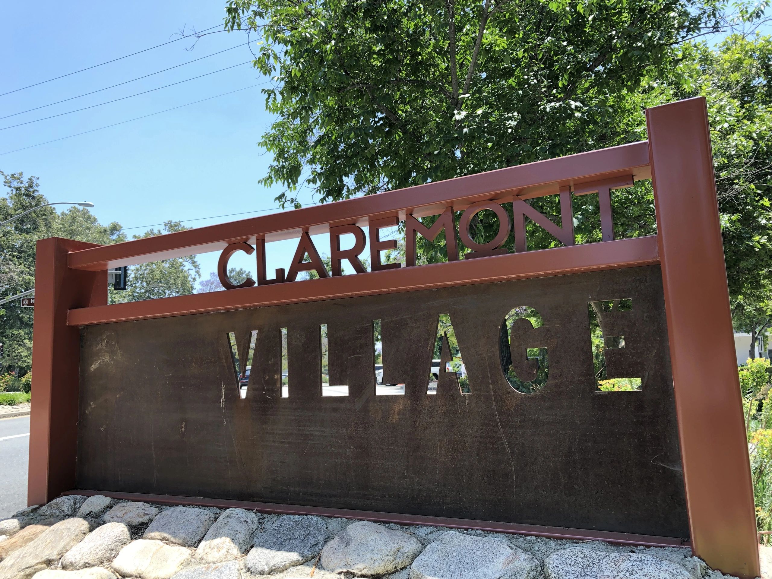 Claremont Village entrance sign beneath leafy trees