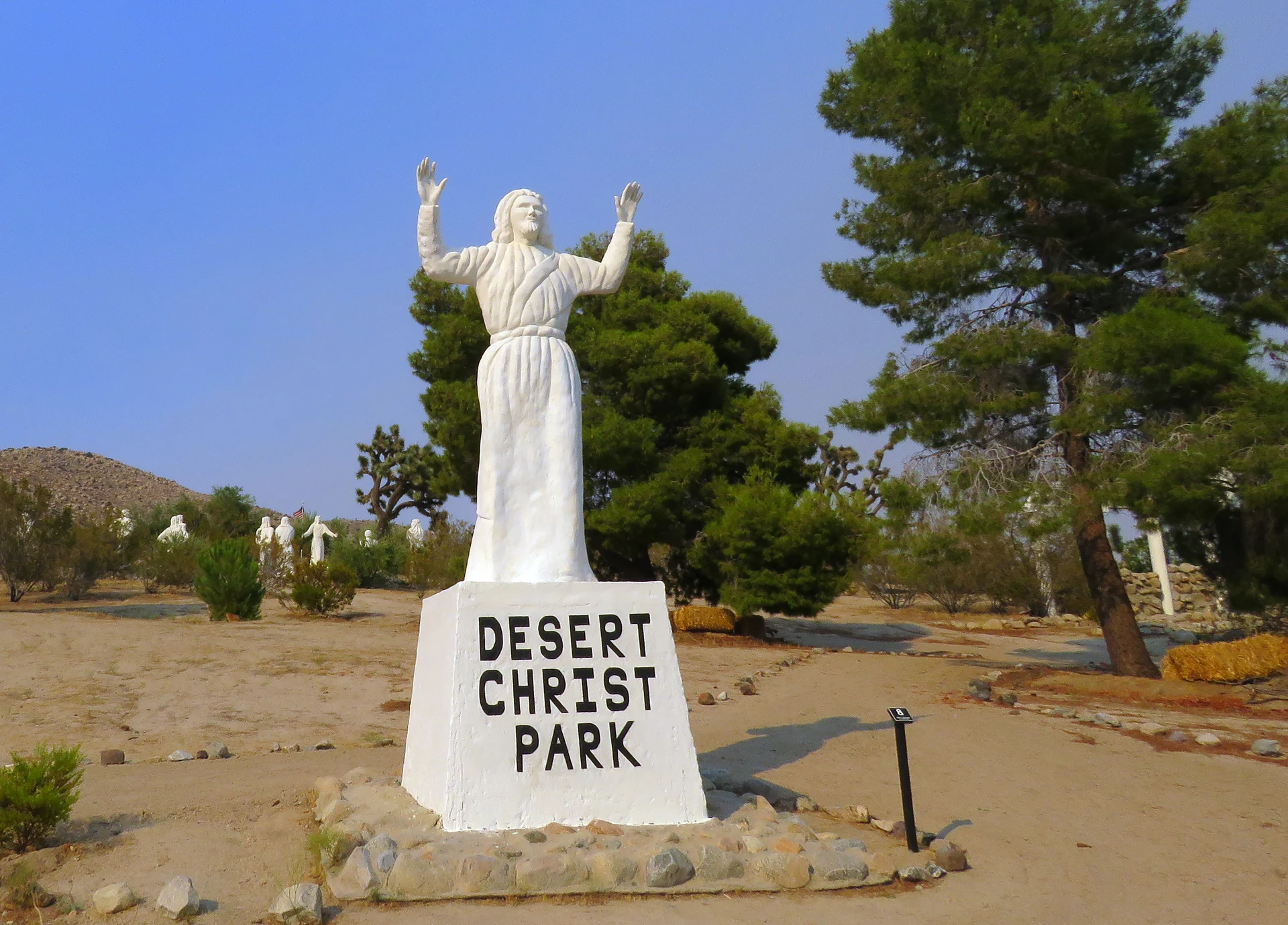 The Blessing Mankind statue beside the Desert Christ Park sign.