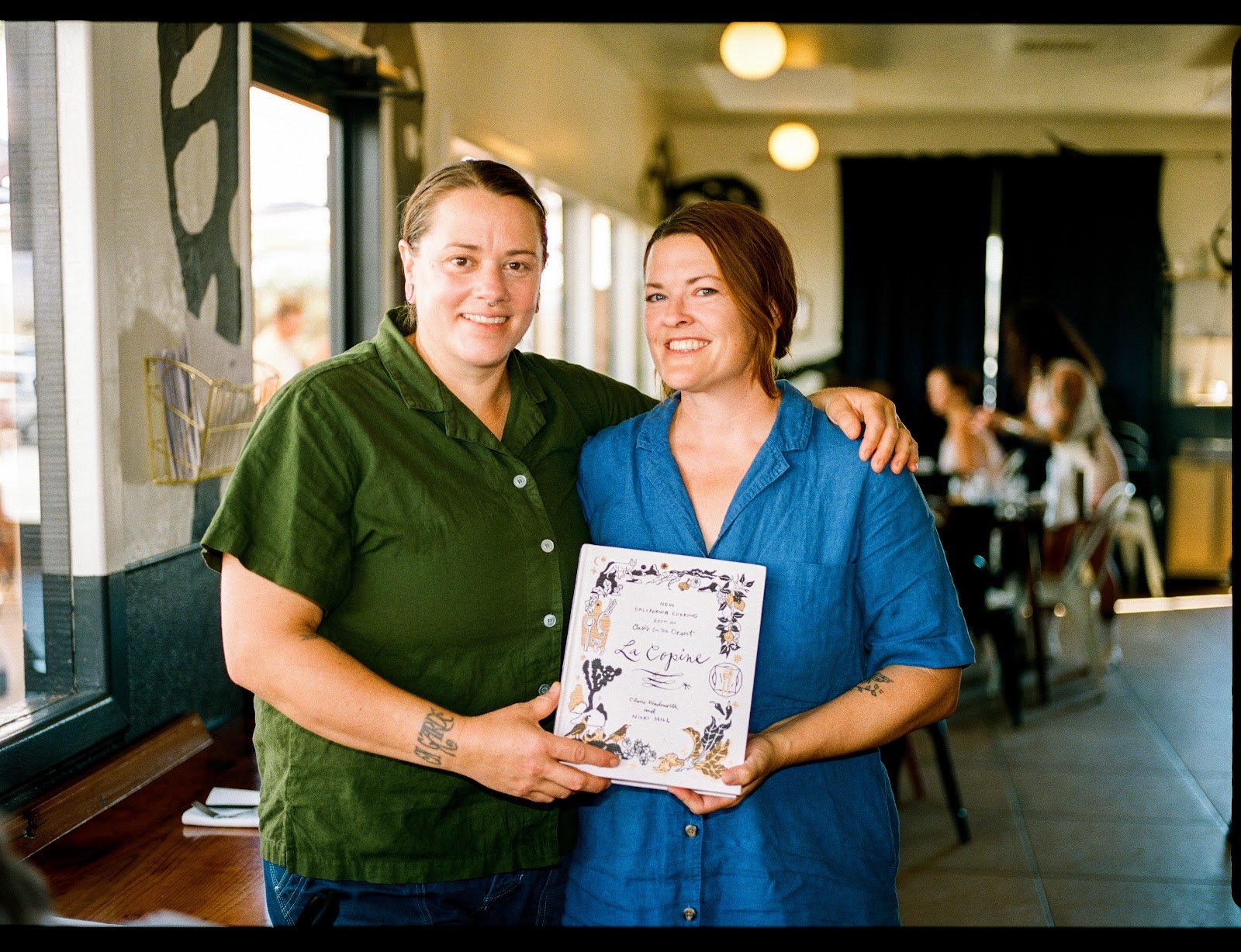 Two La Copine team members holding the restaurant cookbook