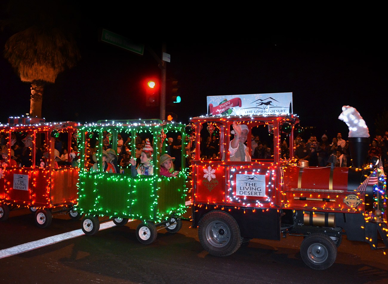 A train-shaped entry decorated with red and green lights at a previous Palm Springs Festival of Lights Parade